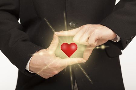 Hands creating a form with shining red heart in the center