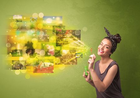 Cute girl blowing colourful glowing memory picture concept on green background