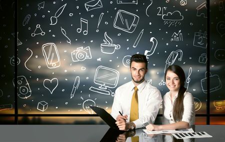 Business couple sitting at table with hand drawn social media icons and symbols

