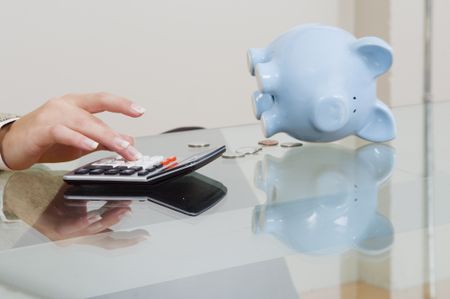 Close up of calculator with piggy bank in background.