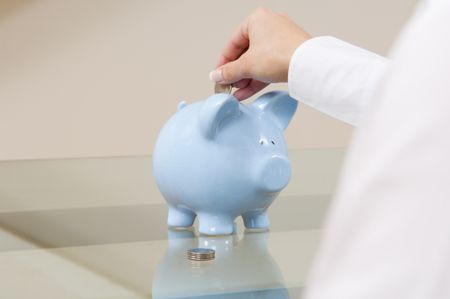 Business woman putting money in piggy bank.