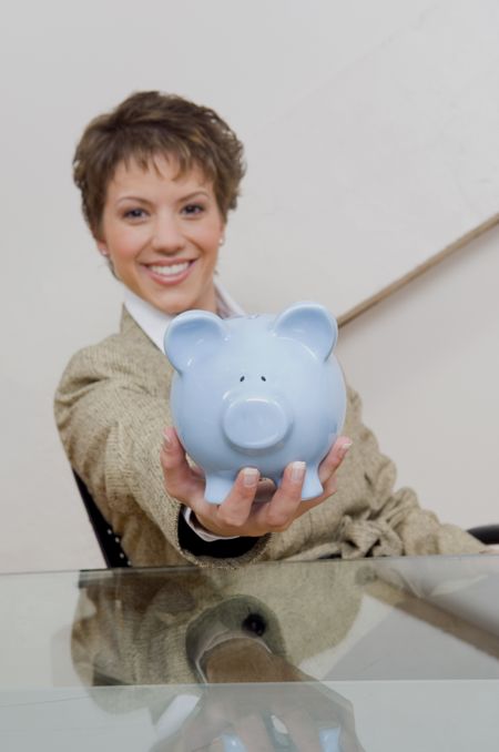 Businesswoman smiling and holding piggy bank.