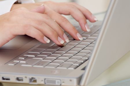 Close up of a woman typing on a laptop.