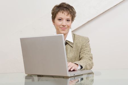 Businesswoman behind computer looking into camera.