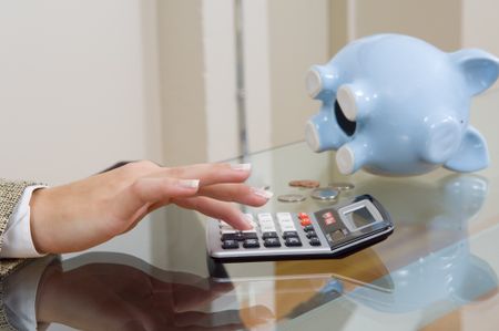 Woman's hands on calculator with piggy bank in background.
