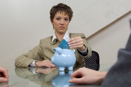 Woman putting a credit card in a piggy bank.