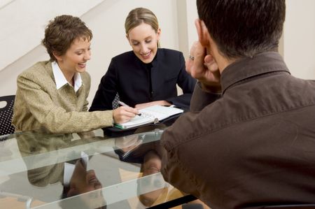 Businesswomen planning a time with guy looking on.