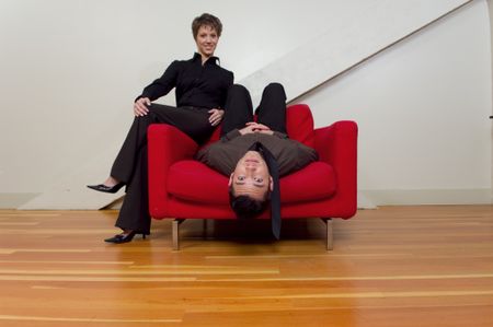 Cool couple relaxing on a red chair.