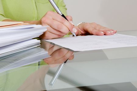 Signing beside a stack of papers.