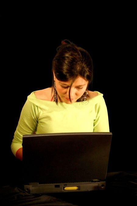 teenager using a laptop over a black background