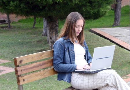 casual woman working on a laptop in a park