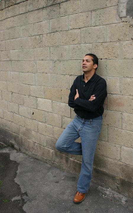 casual guy waiting against a concrete wall