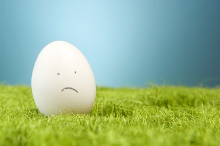 Sad egg on fake green grass.