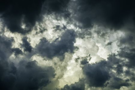 Storm clouds in summer: Ragged wind-driven dark clouds move in quickly to obscure large white billows before sunset, for meteorological themes of instability and rapid change