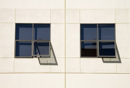 Two similar sets of windows, two shadows, exterior whitewashed wall in sunlight