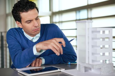 middle eastern descent businessman looking at an architecture model