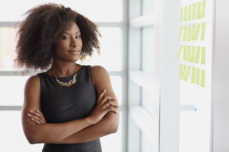 Portrait of a smiling business woman with an afro in bright glass office