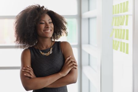 Portrait of a smiling business woman with an afro in bright glass office