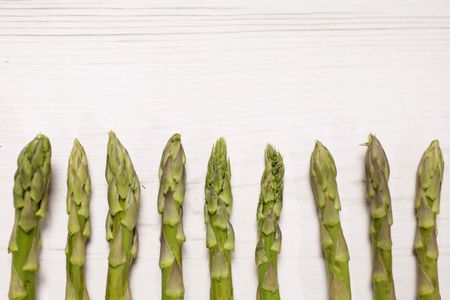 fresh raw asparagus on a light wooden kitchen work surface