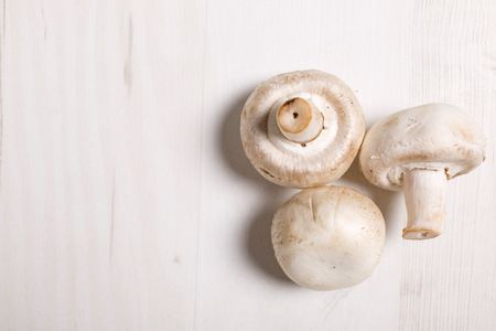 Fresh selection of chestnut mushrooms on a light wooden kitchen surface