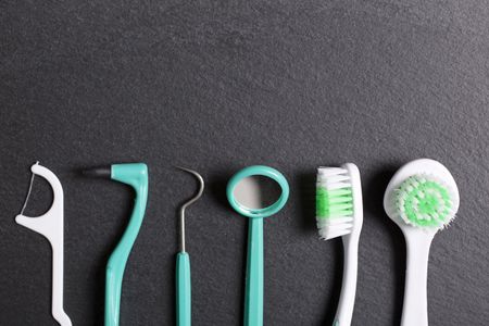 Selection of dentist brushes and tools on a black slate surface