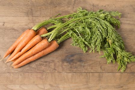 Selection of fresh raw carrots on a wooden kitchen work surface