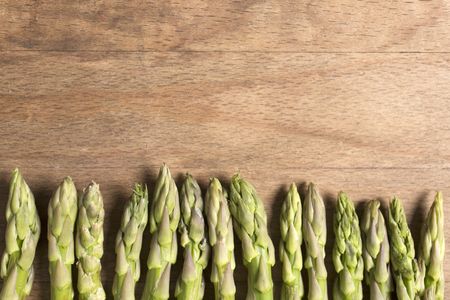 Fresh raw asparagus on a wooden kitchen work surface