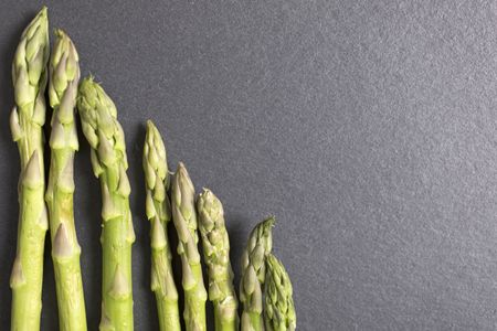 Selection of fresh Asparagus on black slate with copy space