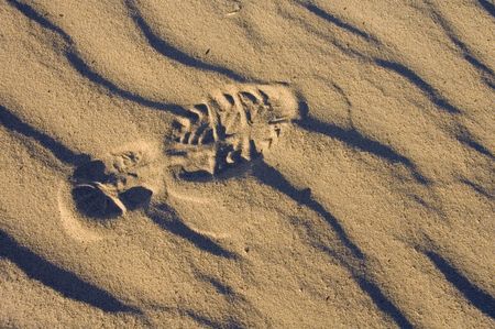 One footprint of a running shoe in wavy sand