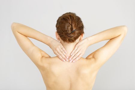 Young woman facing away massaging her neck from an ache or pain