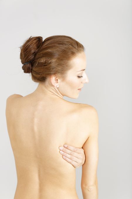 Young woman facing away massaging her lower back from an ache or pain