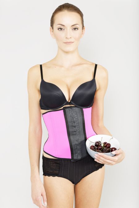 Young woman wearing a waist training corset in black underwear which is the new craze for looking slim
