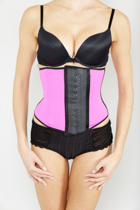 Young woman wearing a waist training corset in black underwear which is the new craze for looking slim
