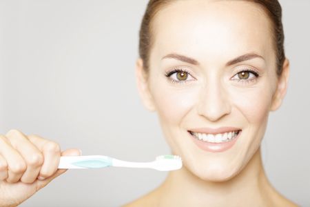 Attractive young woman smiling holding a toothbrush in a beauty style pose