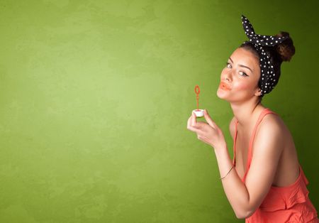 Beautiful woman blowing soap bubble on copyspace green background