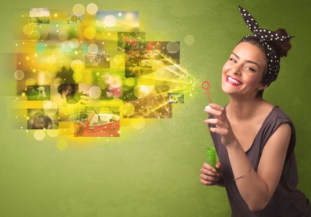 Cute girl blowing colourful glowing memory picture concept on green background