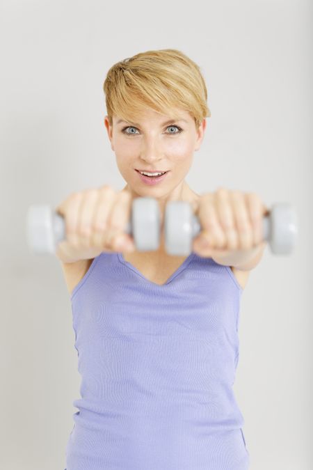 Beautiful young woman exercising with weights at a gym