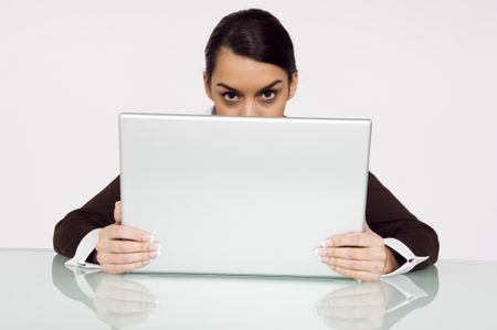 Businesswoman looking over the top of a laptop.