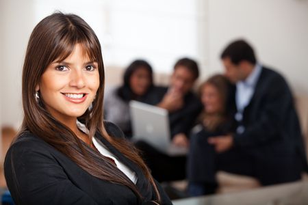 Business woman smiling in an office with her team behind