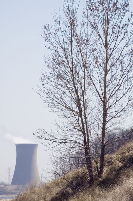 Global warming in brief - tree on hillside in foreground, power plant in background
