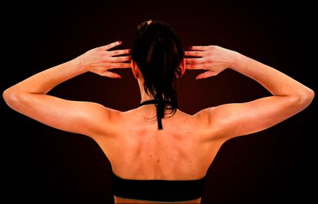 beautiful fit female back during exercise over a dark background