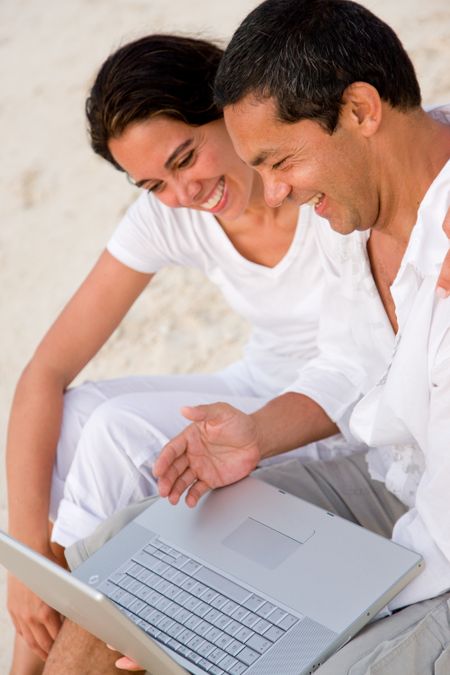 Beach couple on a computer smiling