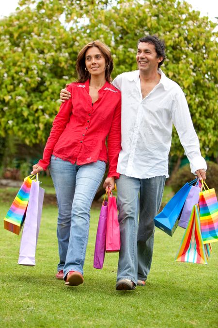 Happy couple of shoppers outdoors with shopping bags