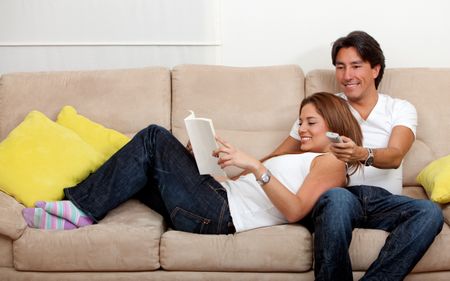 Beautiful couple watching tv and reading on the sofa