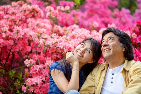 Beautiful portrait of a father and a daughter with flowers behind them