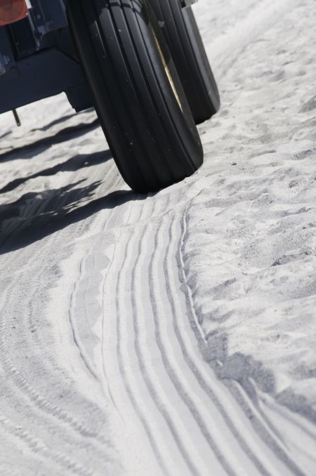 Tire tracks of beach buggy in white sand