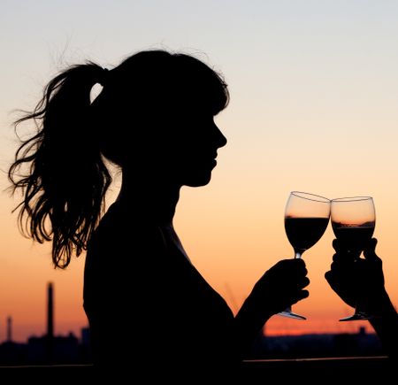 Beautiful couple toasting with wine by the sunset