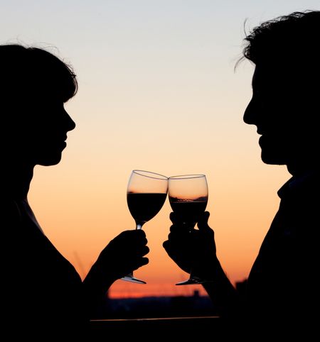 Bautiful couple toasting with wine by the sunset