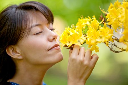 casual woman outdoors smelling some flowers