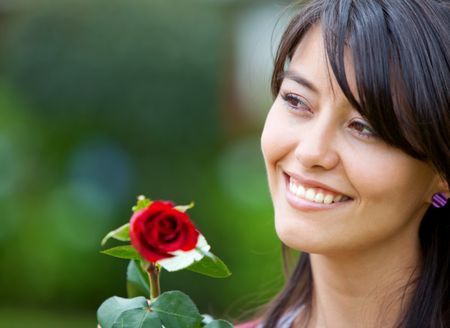 beautiful woman with a rose smiling outdoors